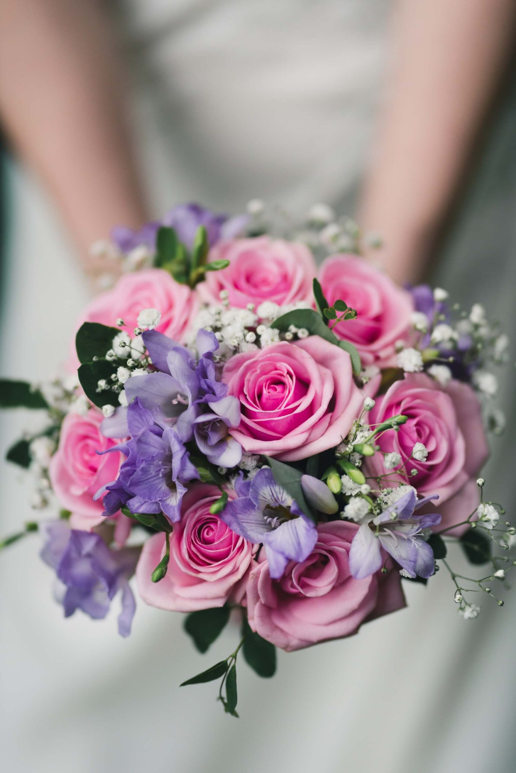 Bröllopsfoto visar färgglad blombukett i fokus hållandes av person